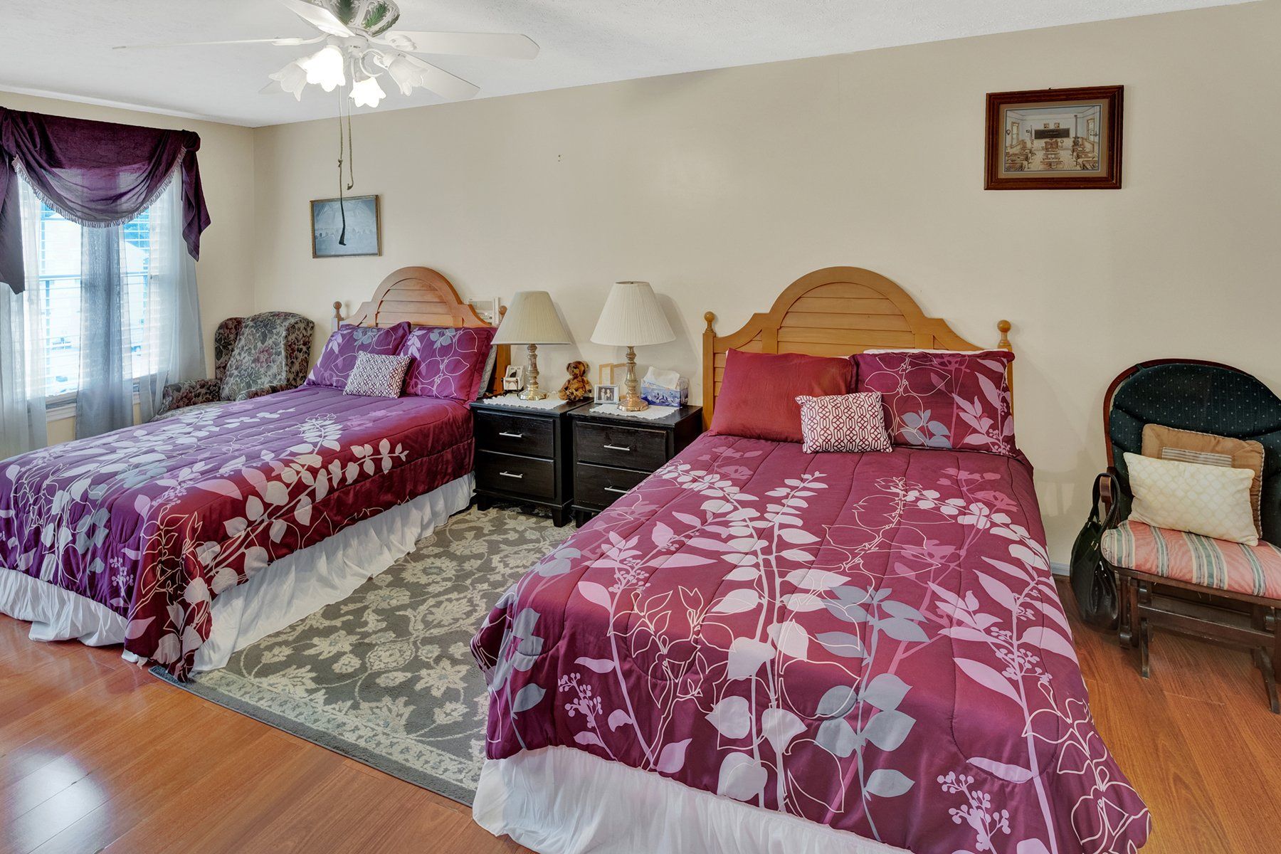 A bedroom with two beds and a ceiling fan