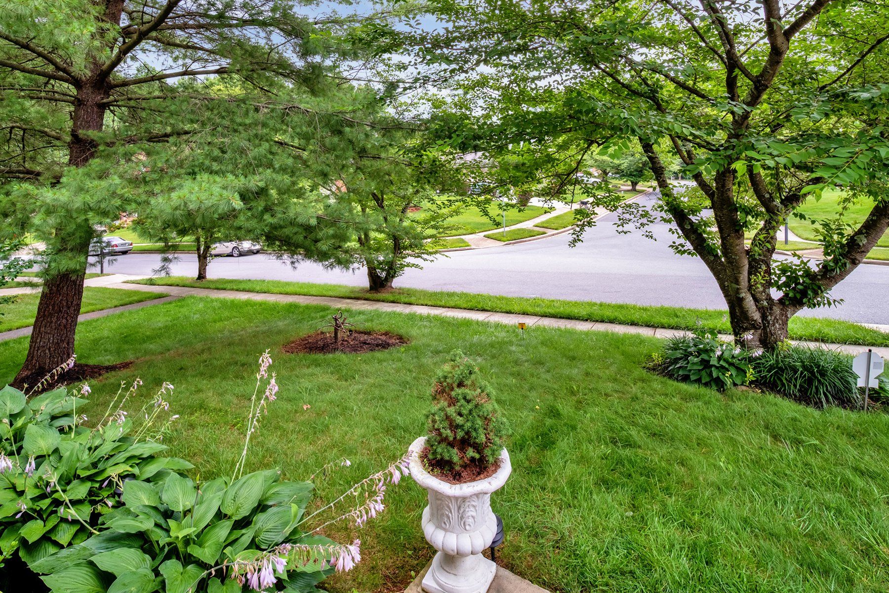 A lawn with a statue in the middle of it and trees in the background.