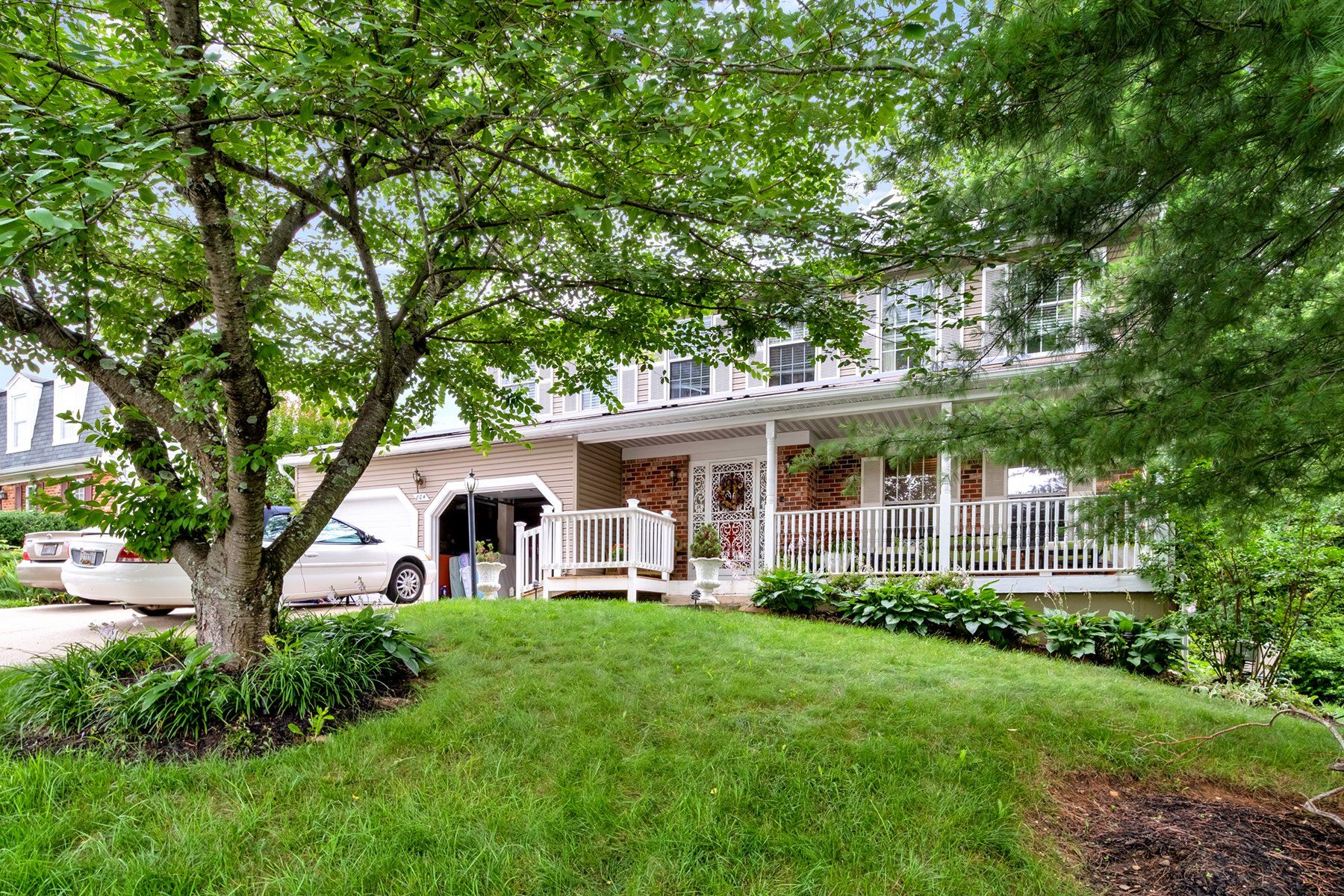 A house with a porch and a car parked in front of it.