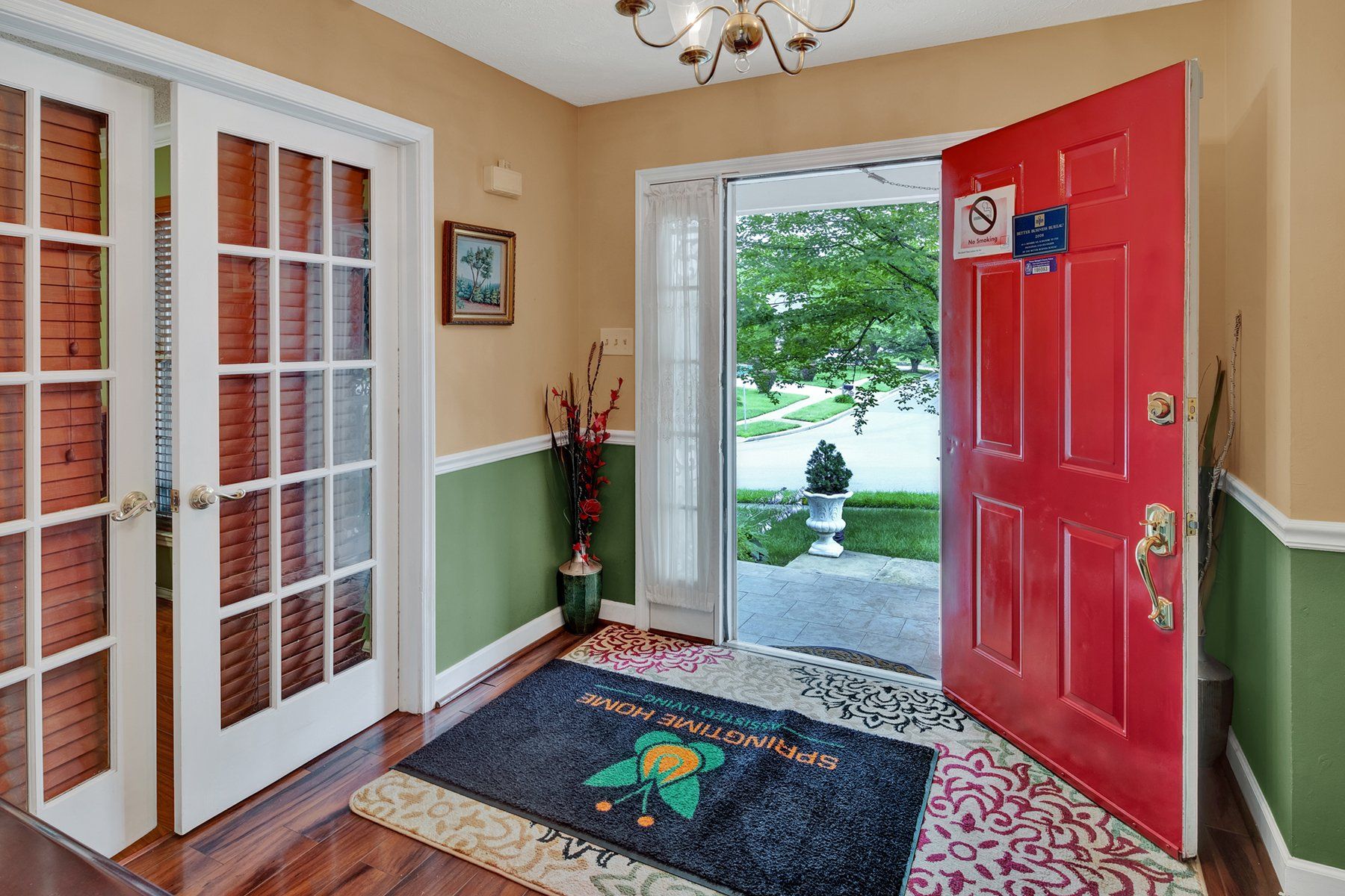 A red door is open in a hallway with a rug on the floor.