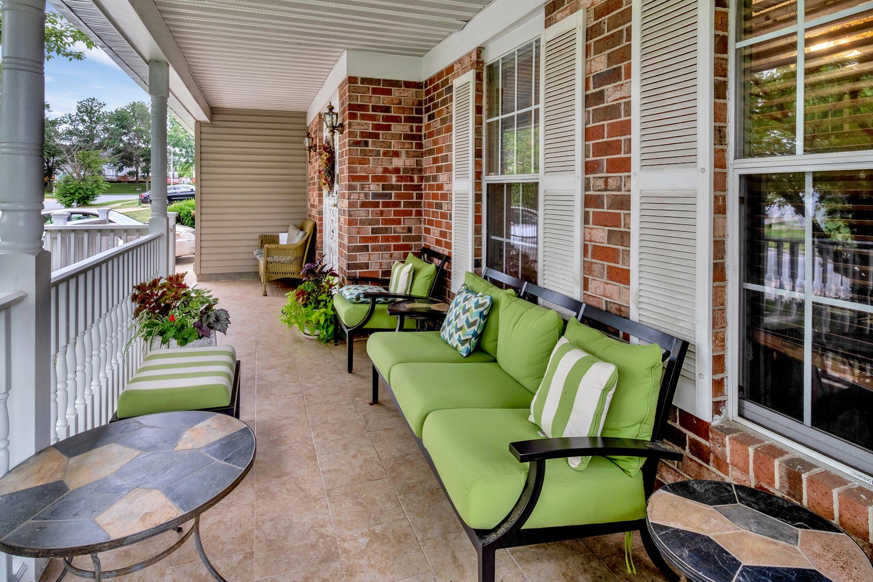 A porch with green furniture and a table.