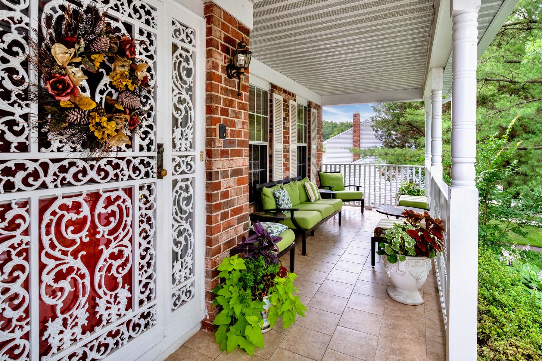 A porch with a couch , chairs and a wreath on the door.