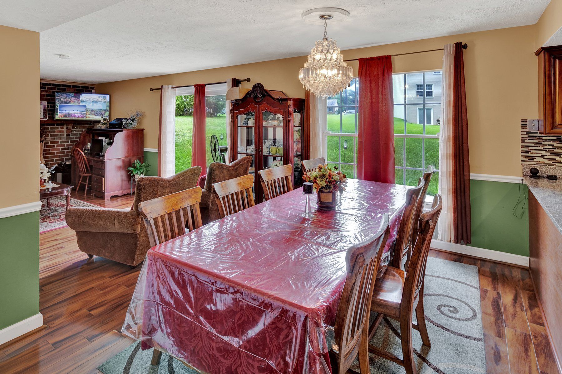 A dining room table with a red tablecloth and chairs in a house.