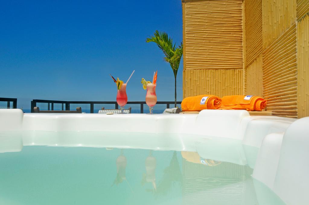 Uma jacuzzi com duas bebidas e toalhas ao lado.