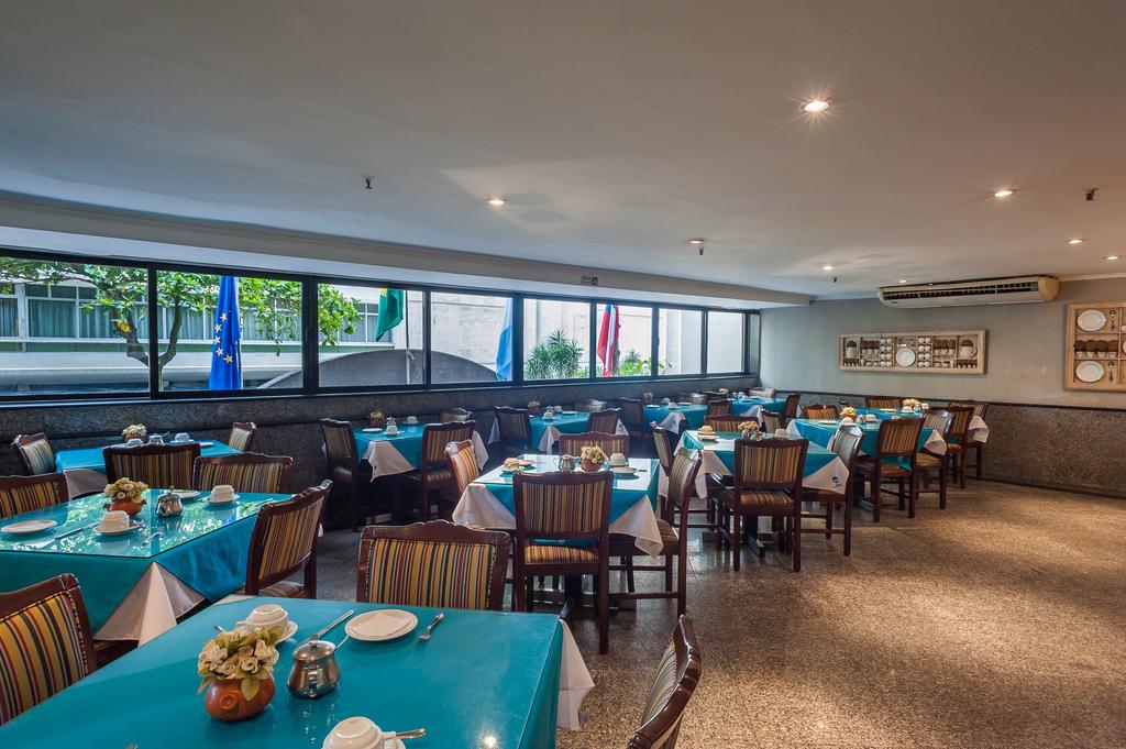Uma grande sala de jantar com mesas e cadeiras e muitas janelas.