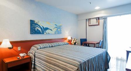 Um quarto de hotel com uma cama king size, mesa e cadeiras.