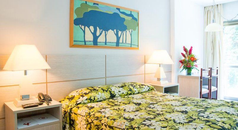 Um quarto de hotel com uma cama grande e uma pintura na parede acima dela.