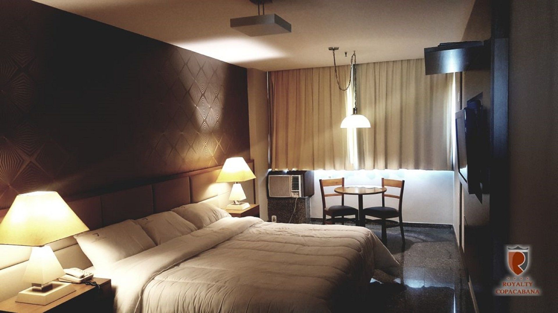 Um quarto de hotel com uma cama grande e duas lâmpadas