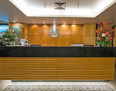 Um lobby de hotel com um balcão preto e paredes de madeira.