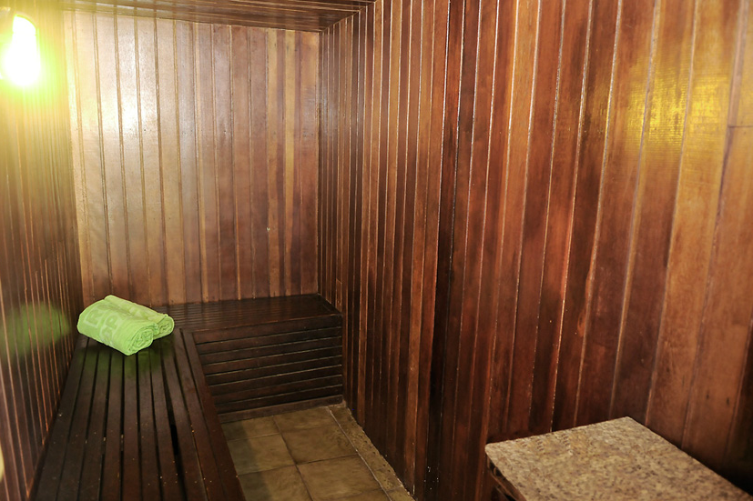 Uma sauna de madeira com uma toalha verde no banco.