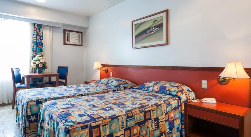 Um quarto de hotel com duas camas, uma mesa e cadeiras.