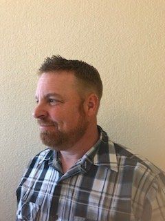 Man in plaid shirt shown in side profile against a beige wall