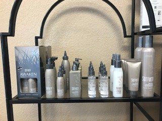 Shelf with assorted skincare bottles and tubes, including a blue AWAKEN box, on a black metal rack