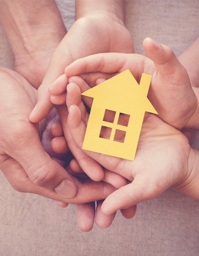 Adult And Child Hands Holding Yellow House — Exton, PA — Longley Insurance Agency
