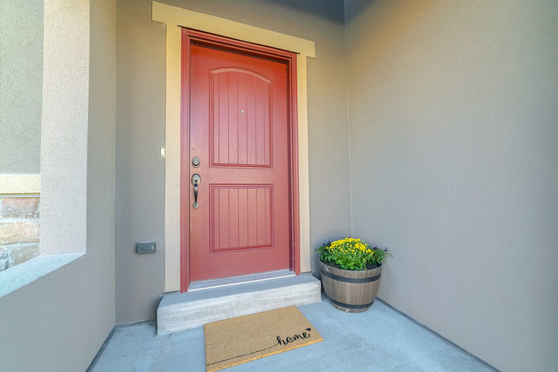 Pink front door with steps, doormat, and a potted plant on a covered porch.
