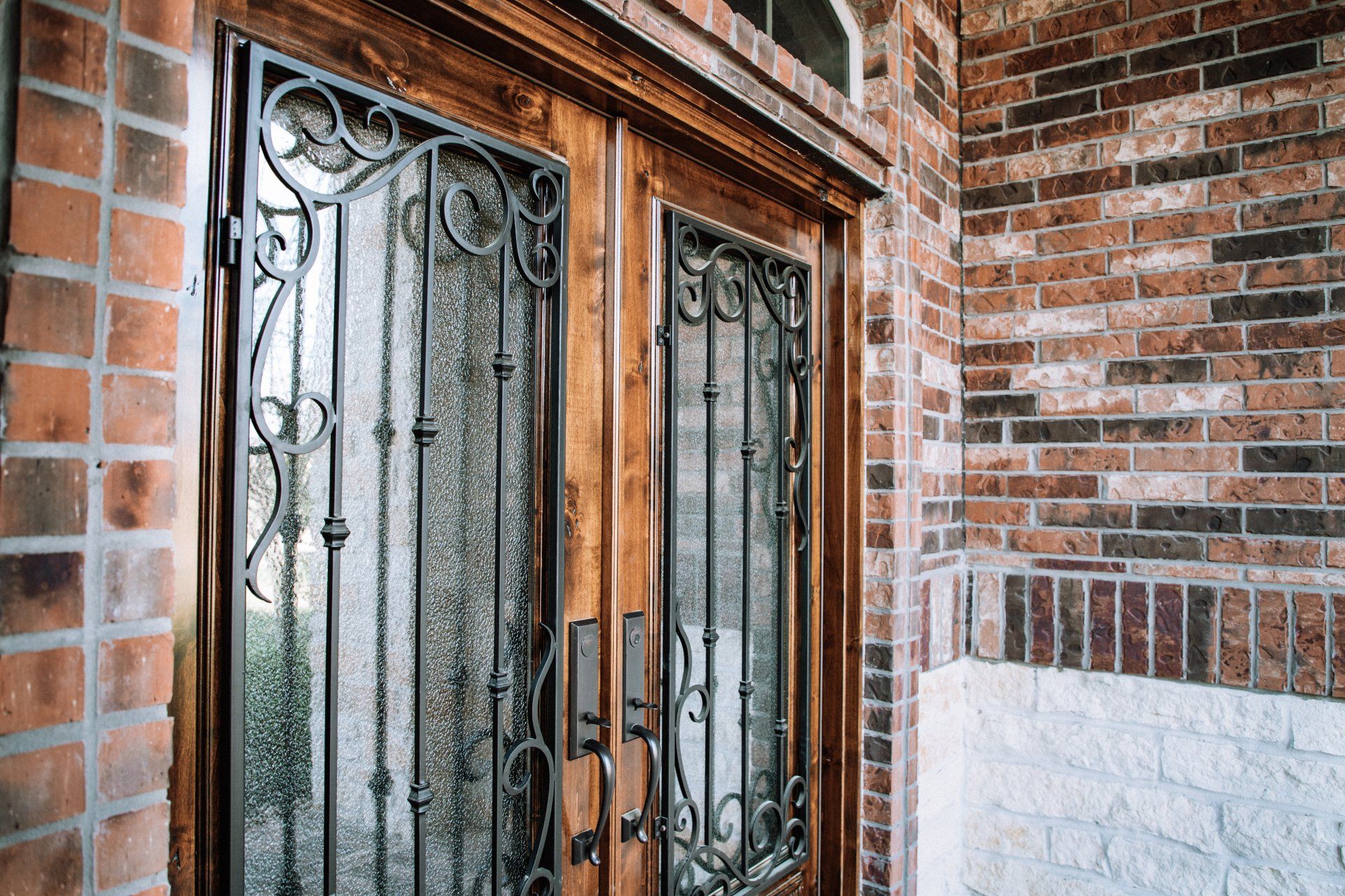 Decorative wrought-iron elevator doors set in a brick-and-stone wall