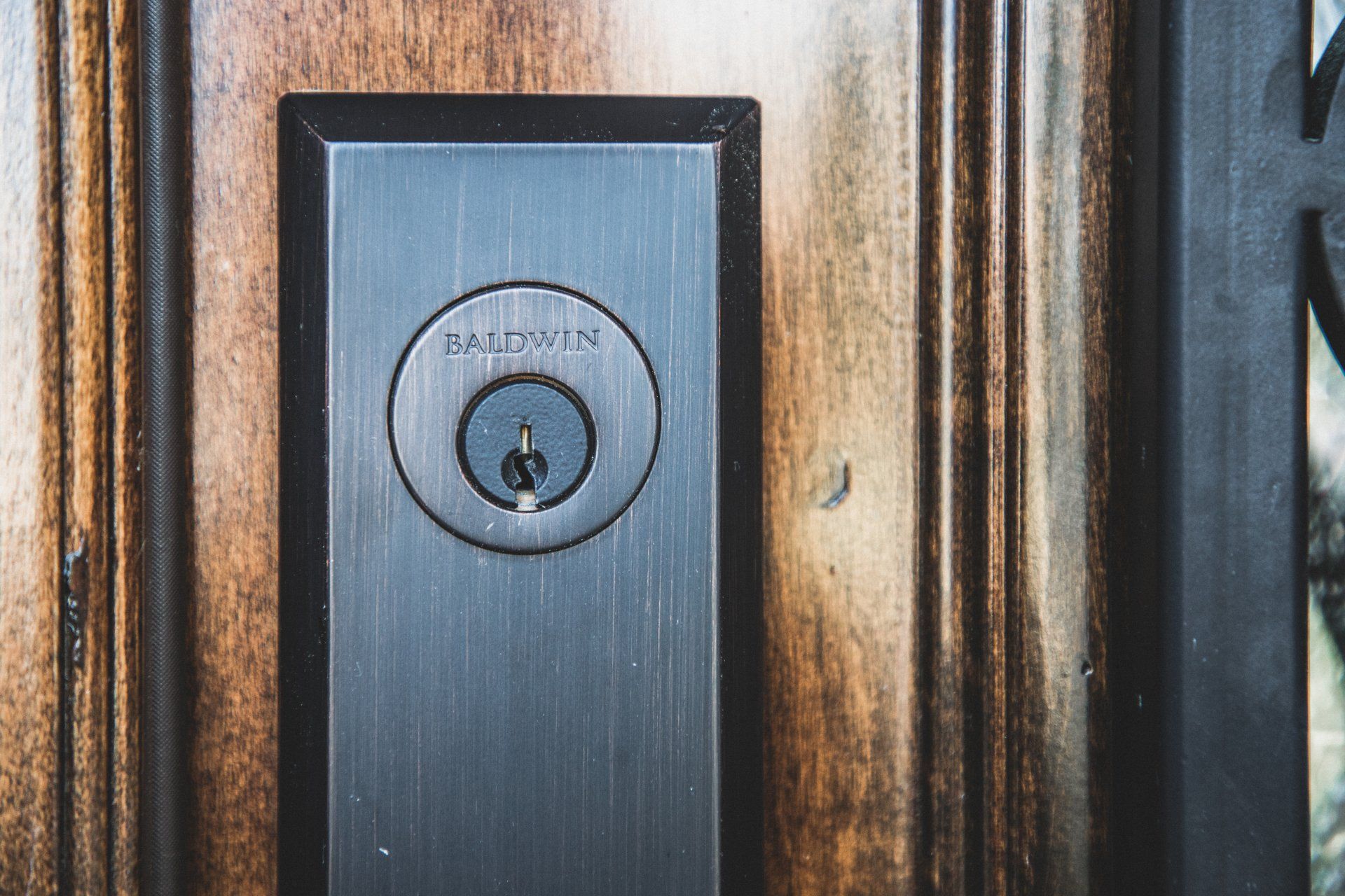 Close-up of a black Schlage door lock on a weathered wooden door