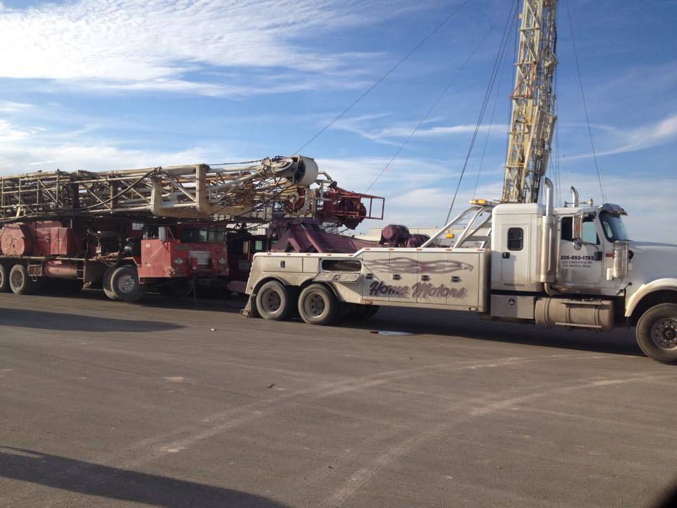 Home Motors, Inc tow truck service towing a work truck of a highway in Big Lake, TX