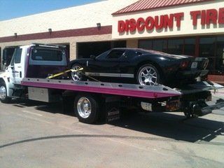 Flatbed towing service outside a storefront in San Angelo, TX