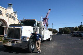 Employee standing next to Home Motors, Inc tow truck service fleet vehicle in Winters, TX