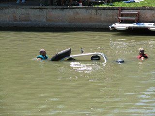 Tow truck service assisting with auto recovery for people in the water near sinking boat