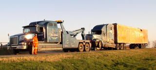 Towing company providing rotator tow truck service for a tractor trailer on the side of the highway in Winters, TX