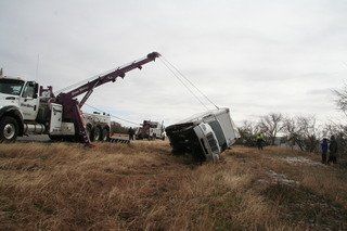 Tow truck service vehicle pulling a wrecked semi truck upright