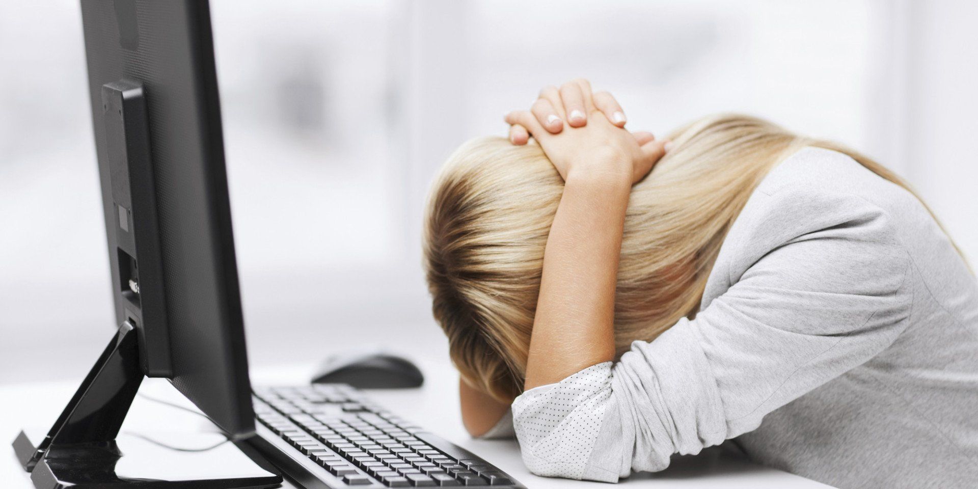 a woman is sitting in front of a computer with her head in her hands