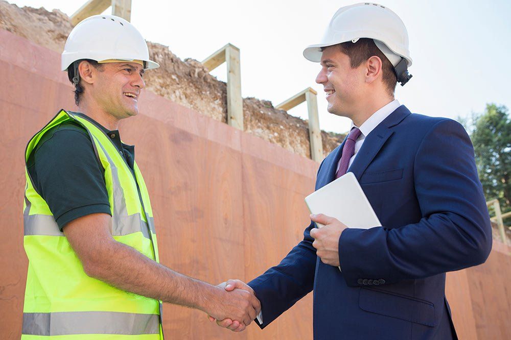 builder shaking hands with commercial businessman with hardhats on
