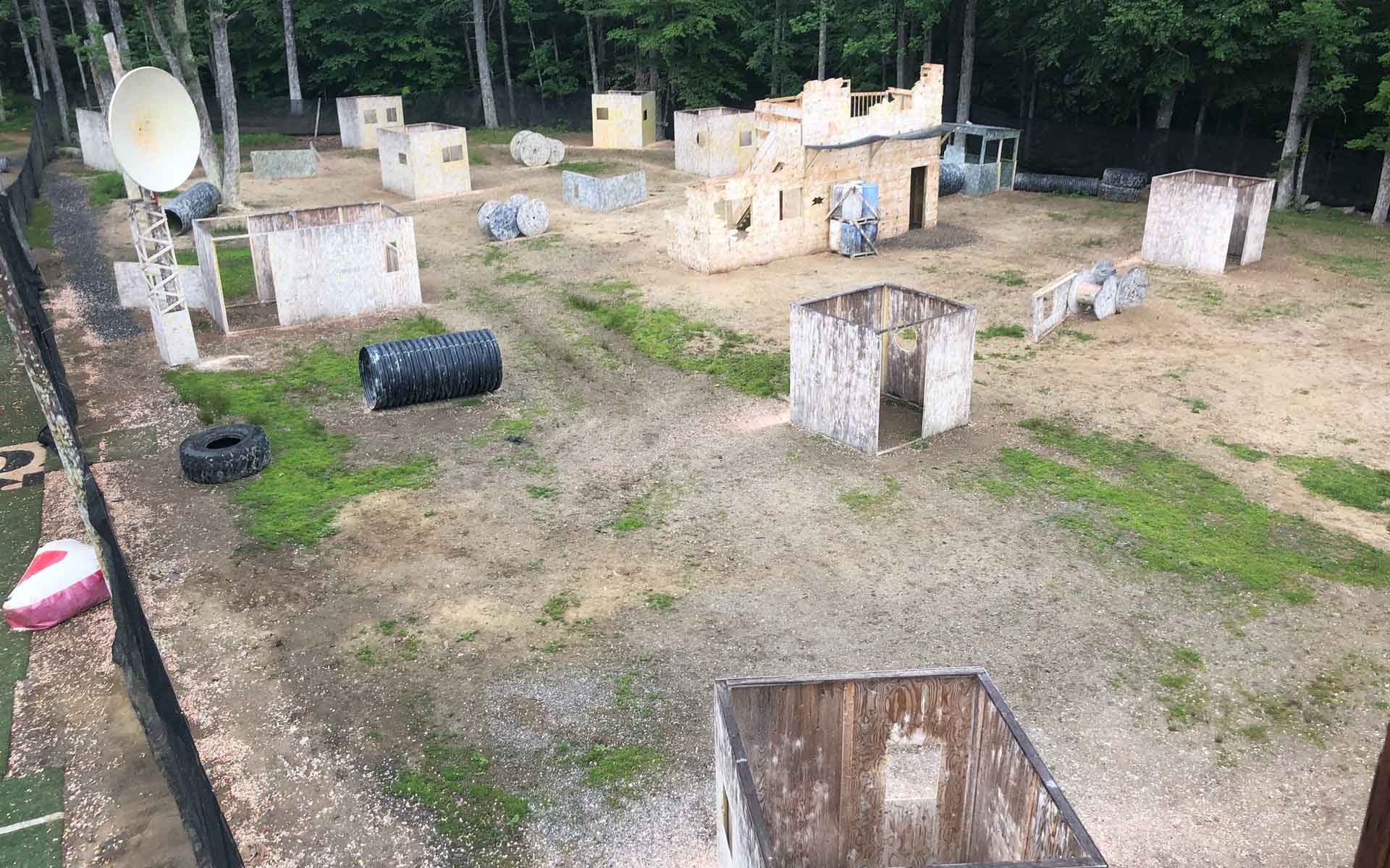 Paintball field with bunkers, structures, and trees in the background.