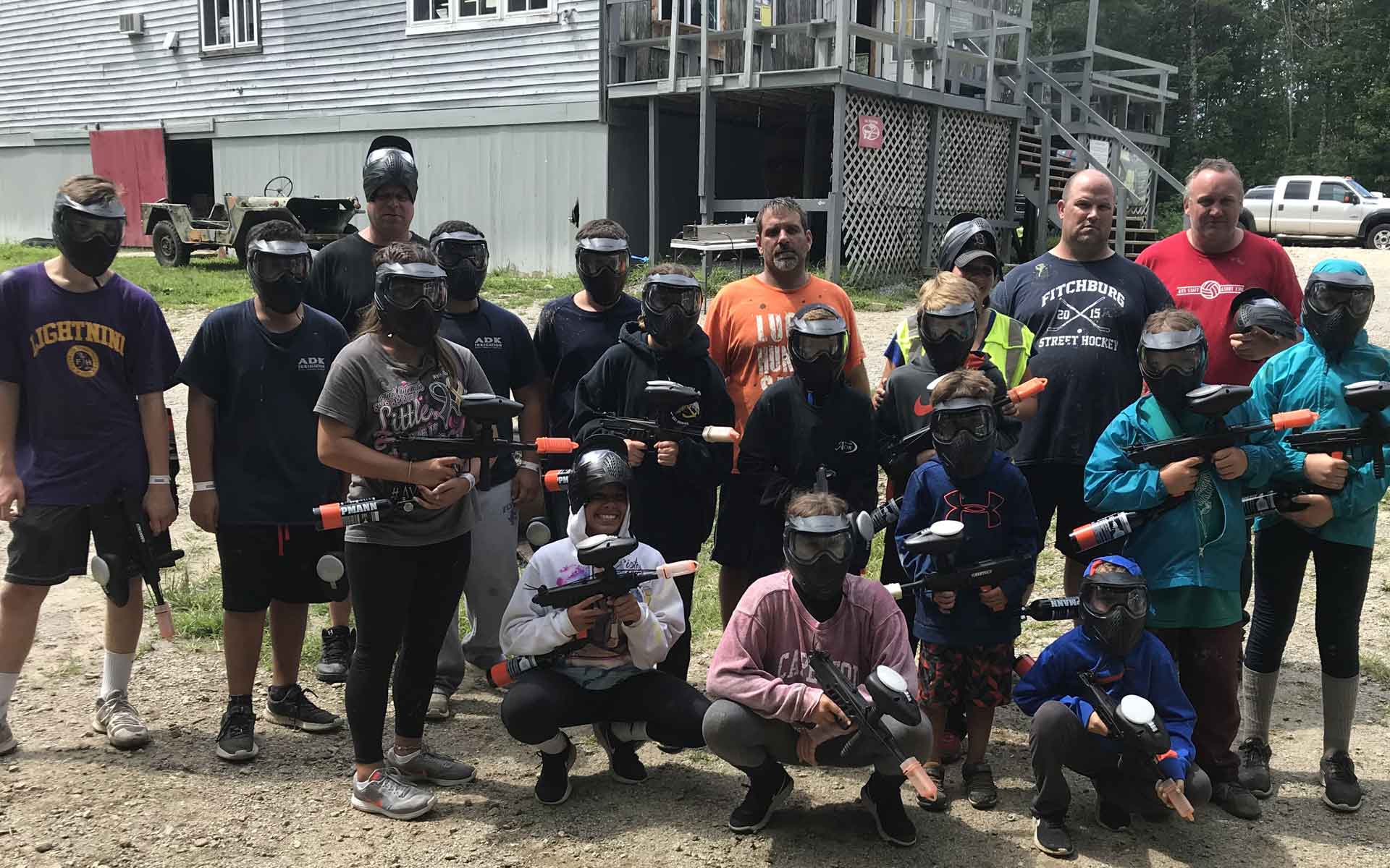 Group of people with paintball gear posing outdoors in front of a building.