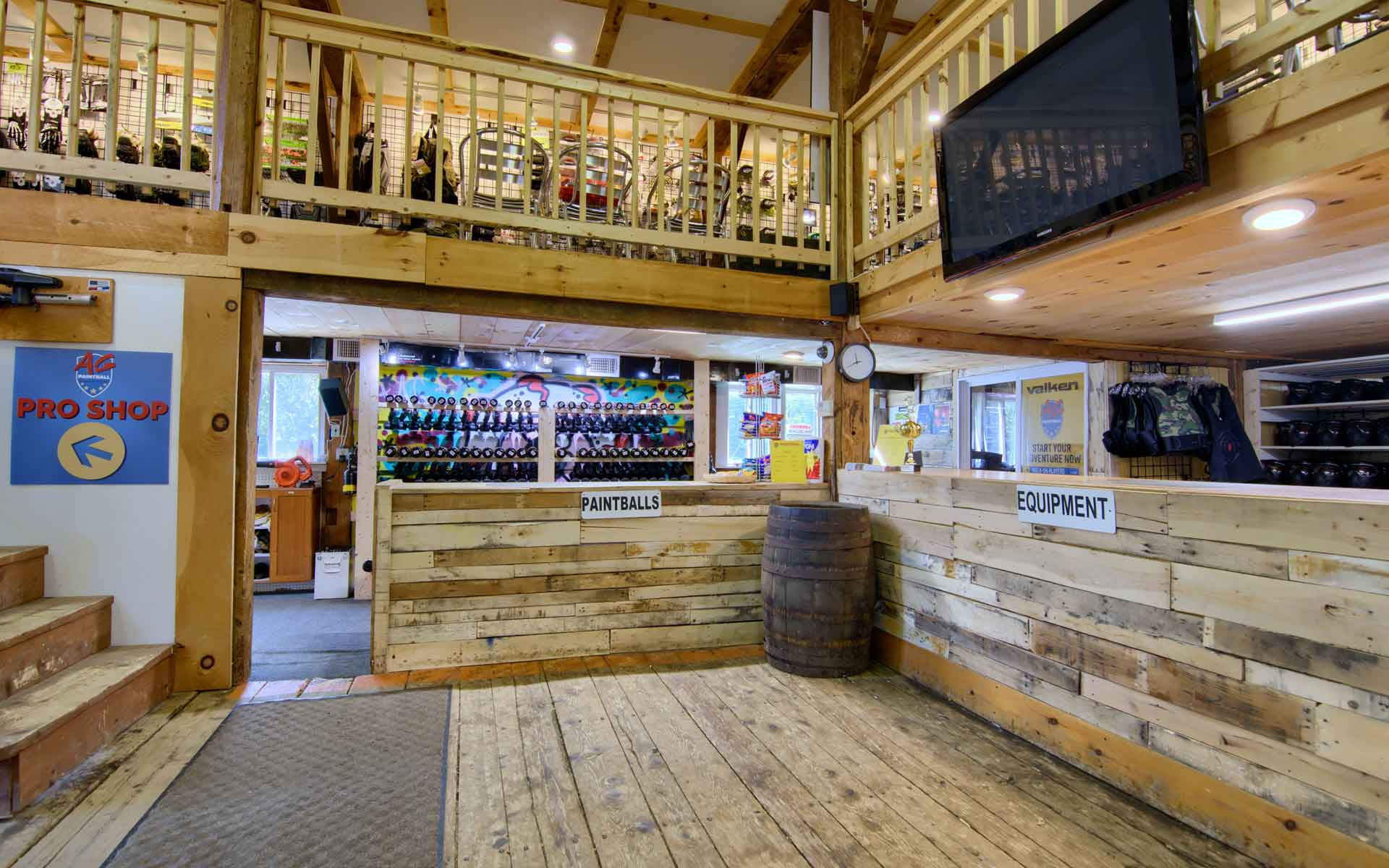 Interior of a ski shop, with a loft, wood paneling, and a TV, beer bottles on display.