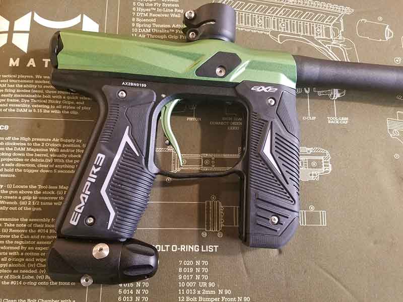 Green and black Empire paintball gun on a green mat with text.