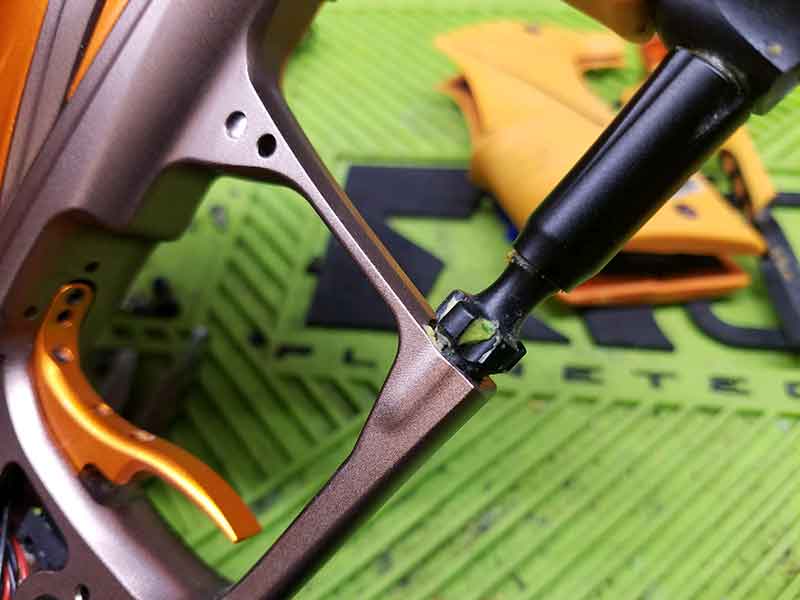 Close-up of a paintball gun's metallic frame with an orange trigger and black nozzle.