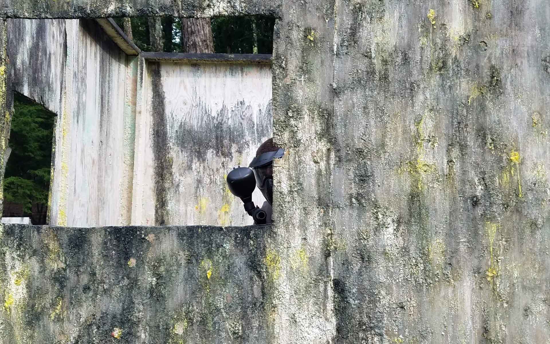 A person peeks out of a weathered concrete structure's window, partially obscured.