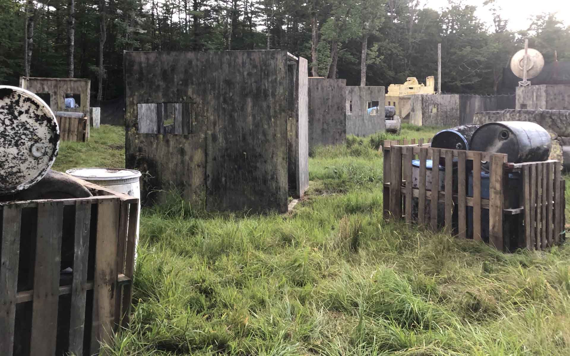 Paintball field with wooden bunkers and grassy terrain.