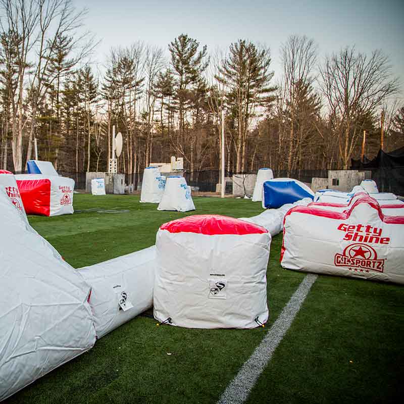 Paintball field with inflatable bunkers on a green turf field.