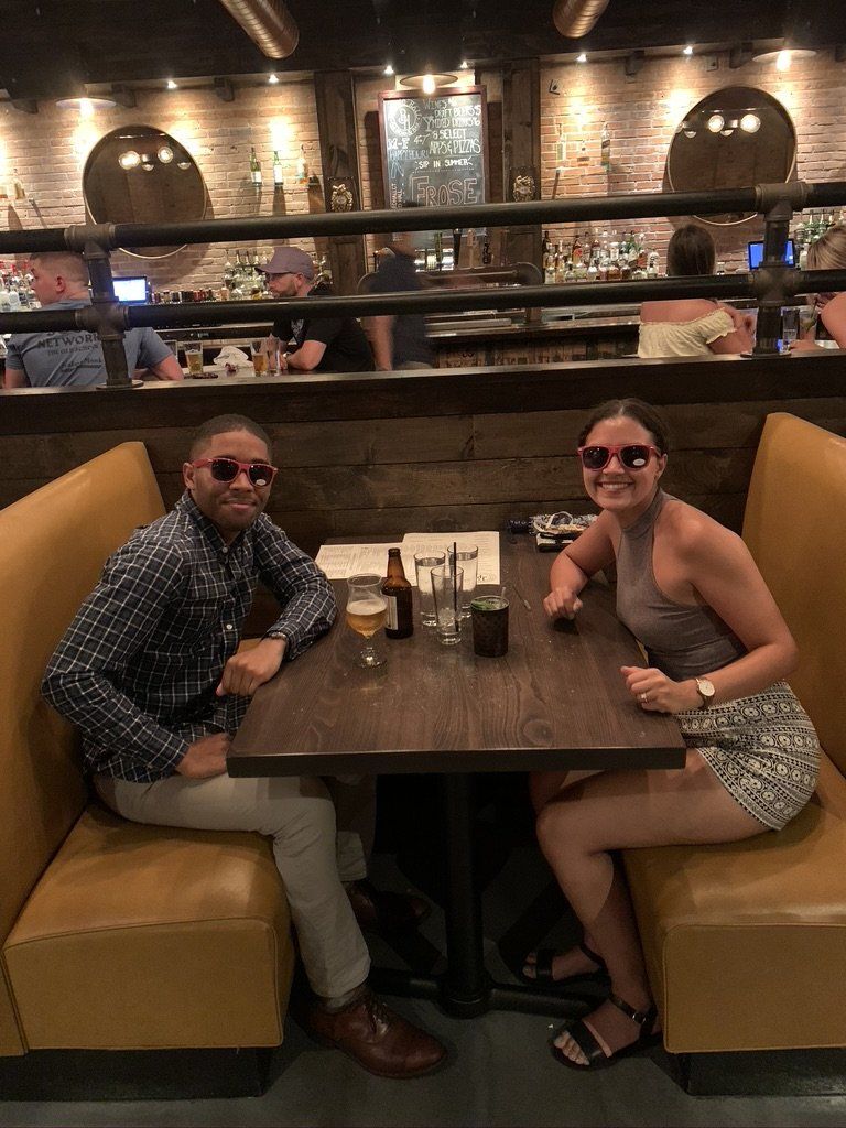 Two people in sunglasses sit at a booth in a dimly lit restaurant.