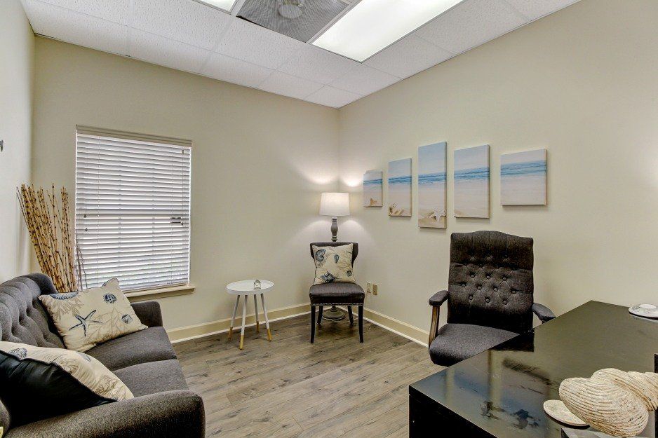 Cozy beige office or waiting room with gray chairs, lamp, wall art, and a window with blinds