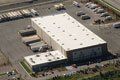 An aerial view of a large building with a white roof in a parking lot.