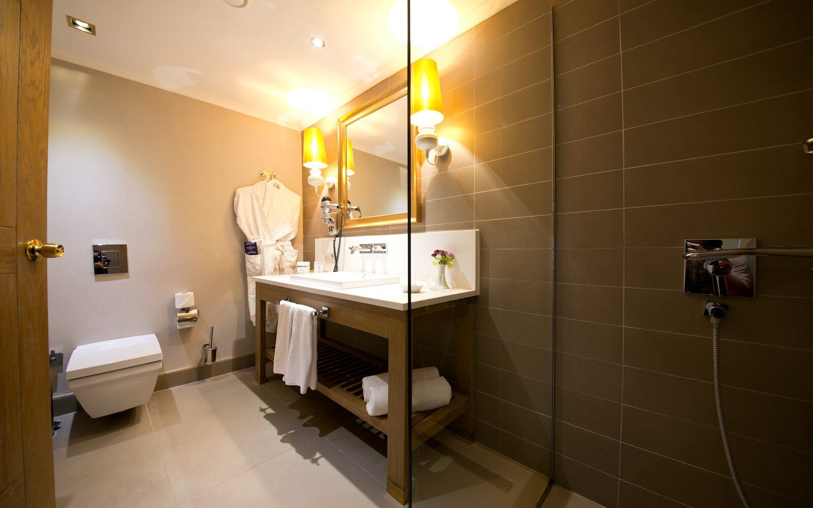 Ein Badezimmer mit Toilette, Waschbecken, Spiegel und ebenerdiger Dusche.