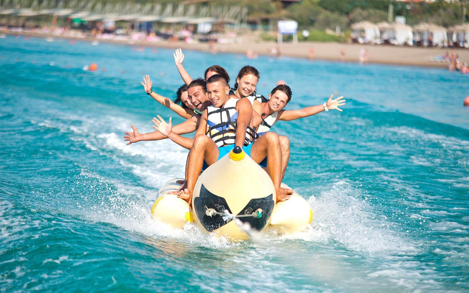 Eine Gruppe Leute fährt auf einem Bananenboot im Meer.