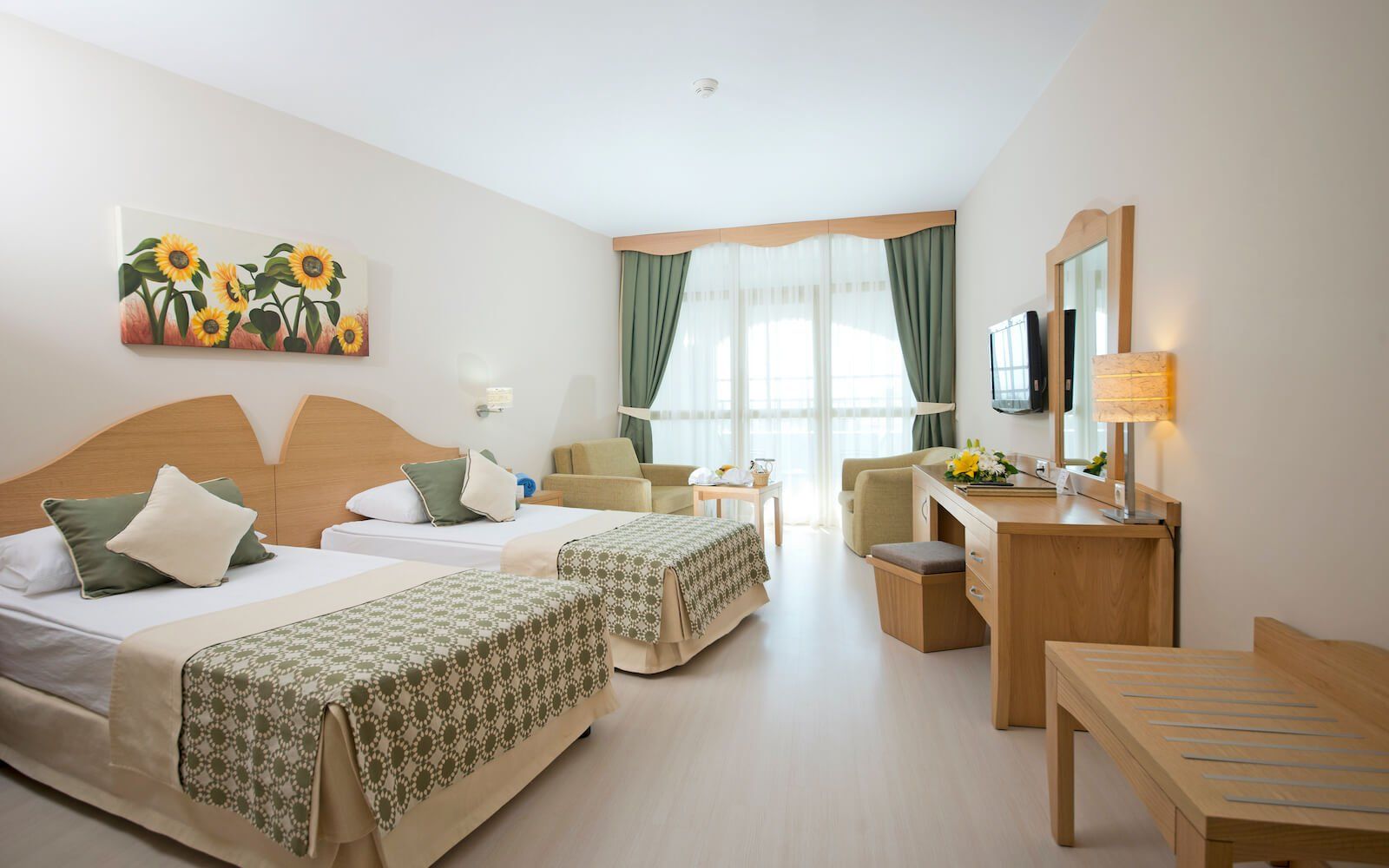 Ein Hotelzimmer mit zwei Betten, einem Schreibtisch, einem Stuhl und einem Fernseher.