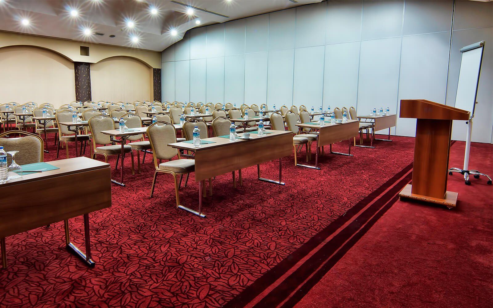 Ein großer Konferenzraum mit Tischen und Stühlen sowie einem Podium