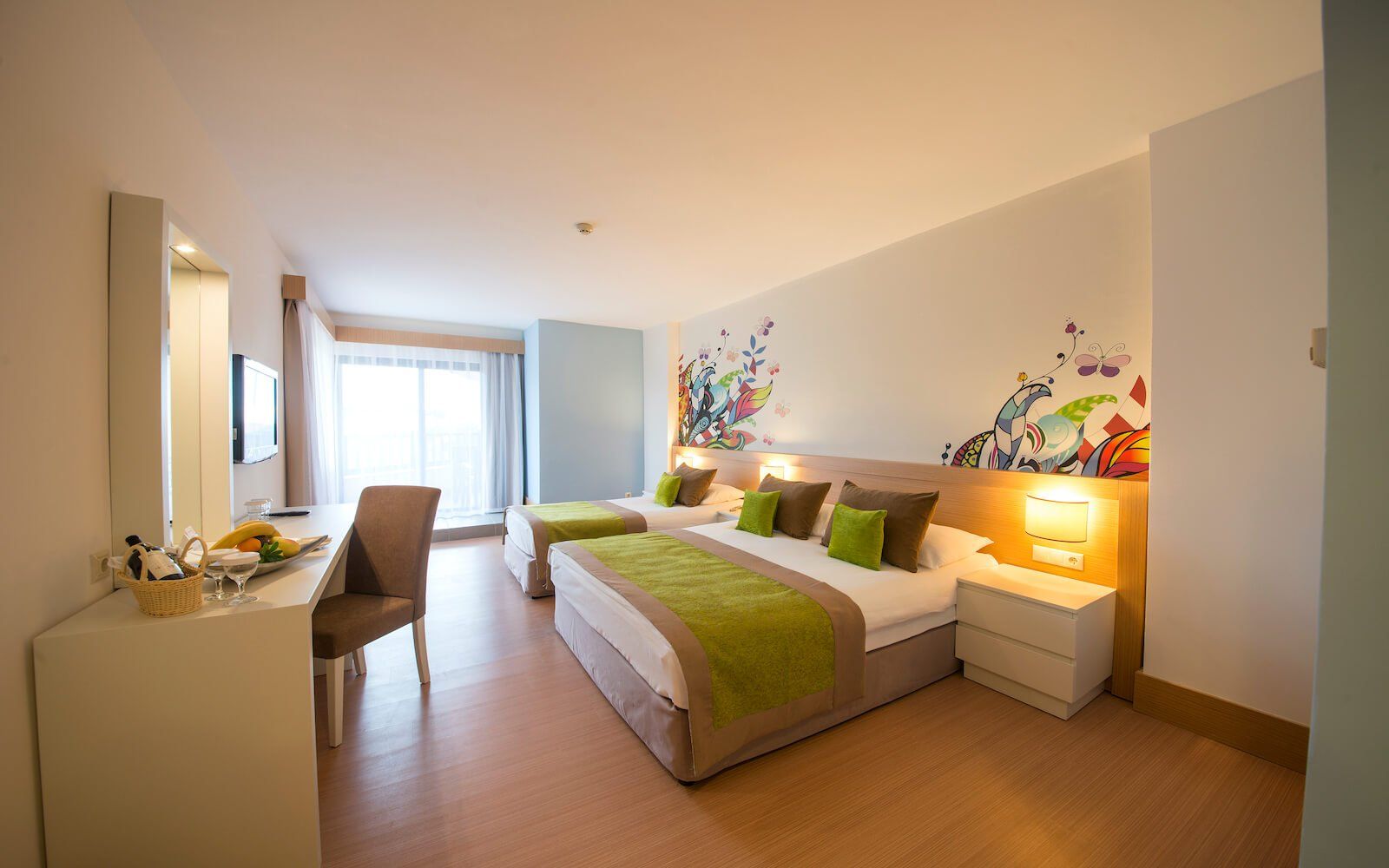 Ein Hotelzimmer mit drei Betten und einem Schreibtisch.
