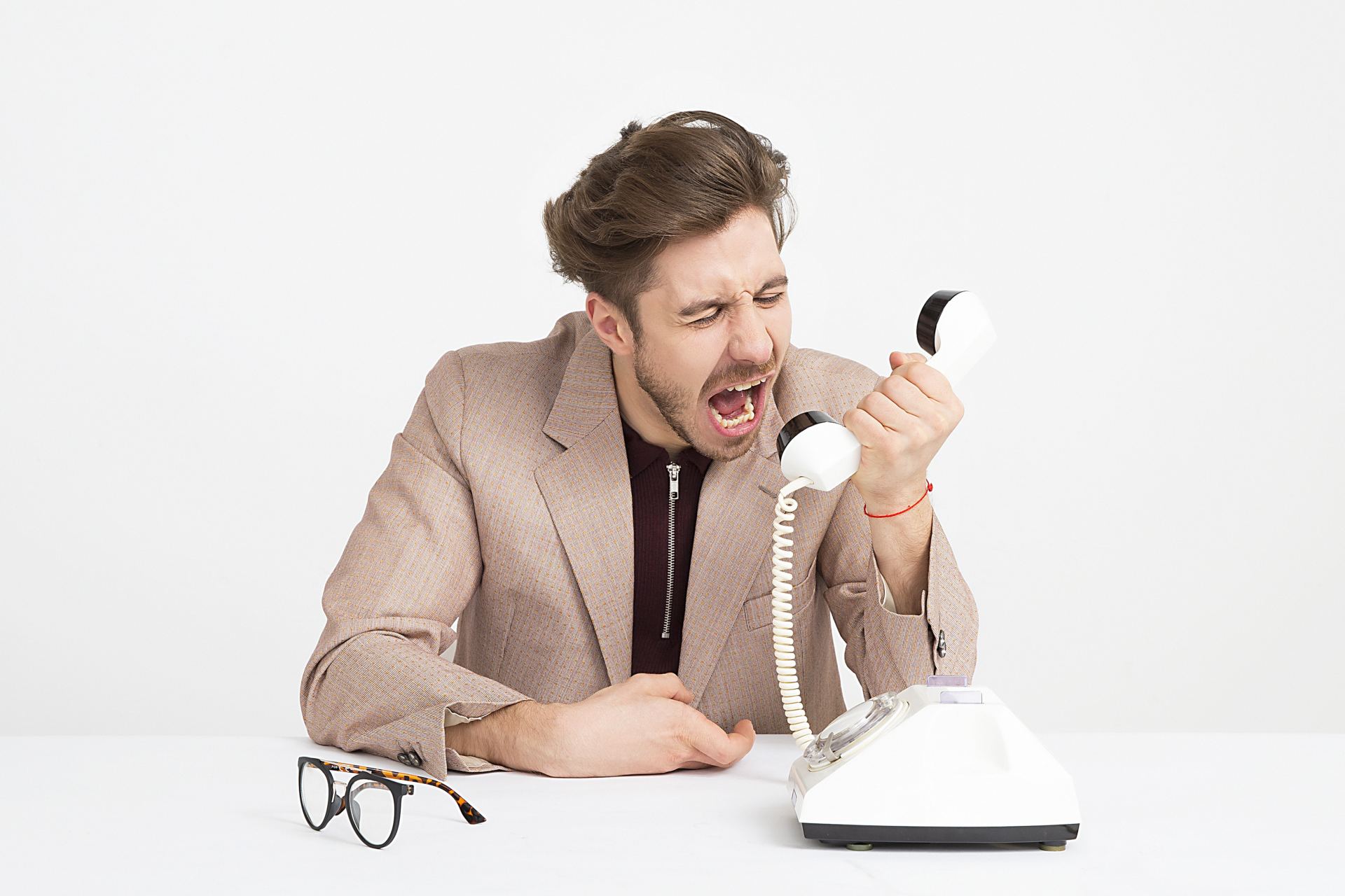 a man is sitting at a table screaming into a telephone .