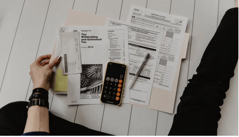 a person is sitting on the floor with papers and a cell phone .