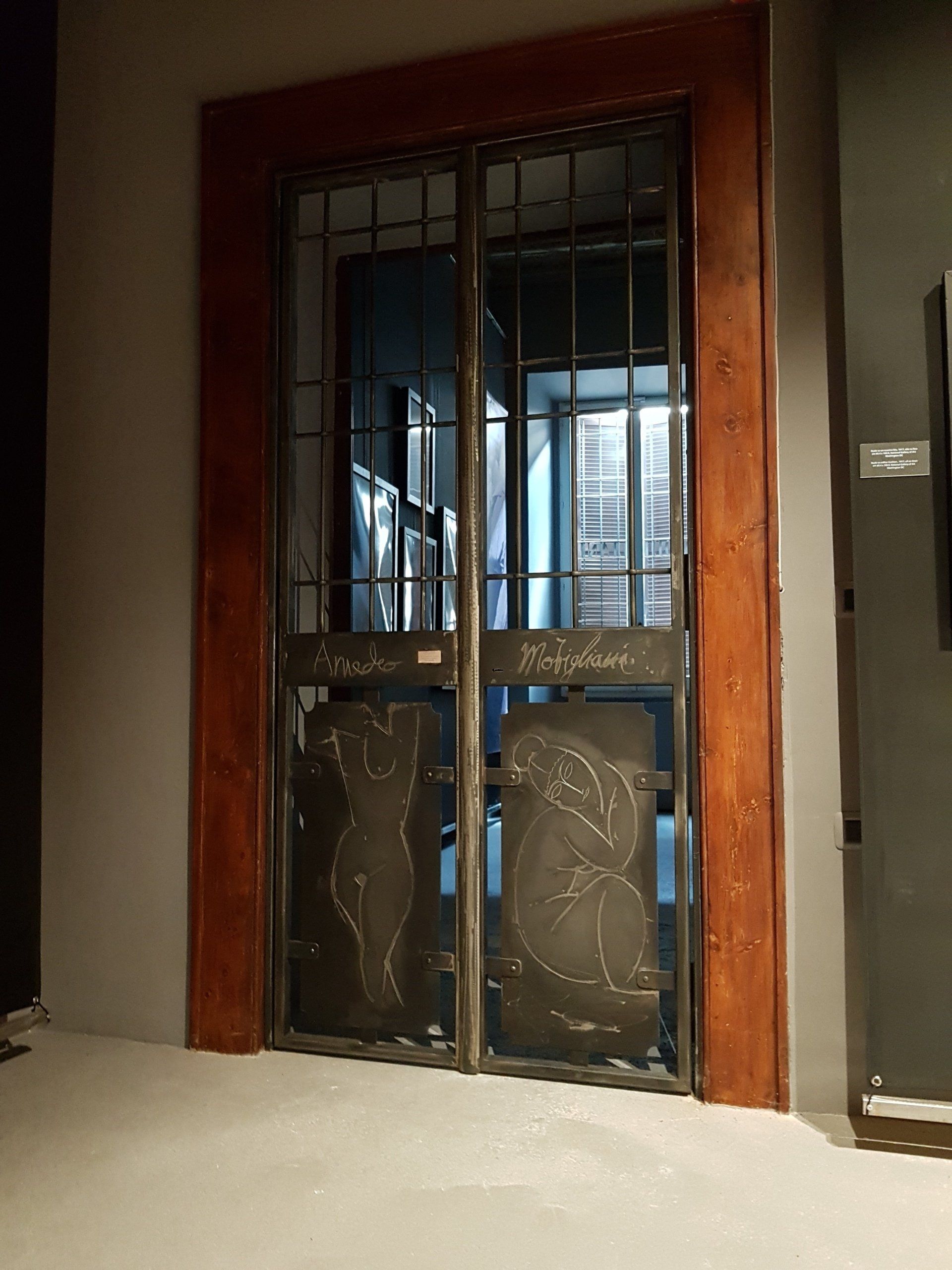 Porte dell'ascensore chiuse, in metallo e vetro, con pannelli decorativi, in un corridoio poco illuminato.