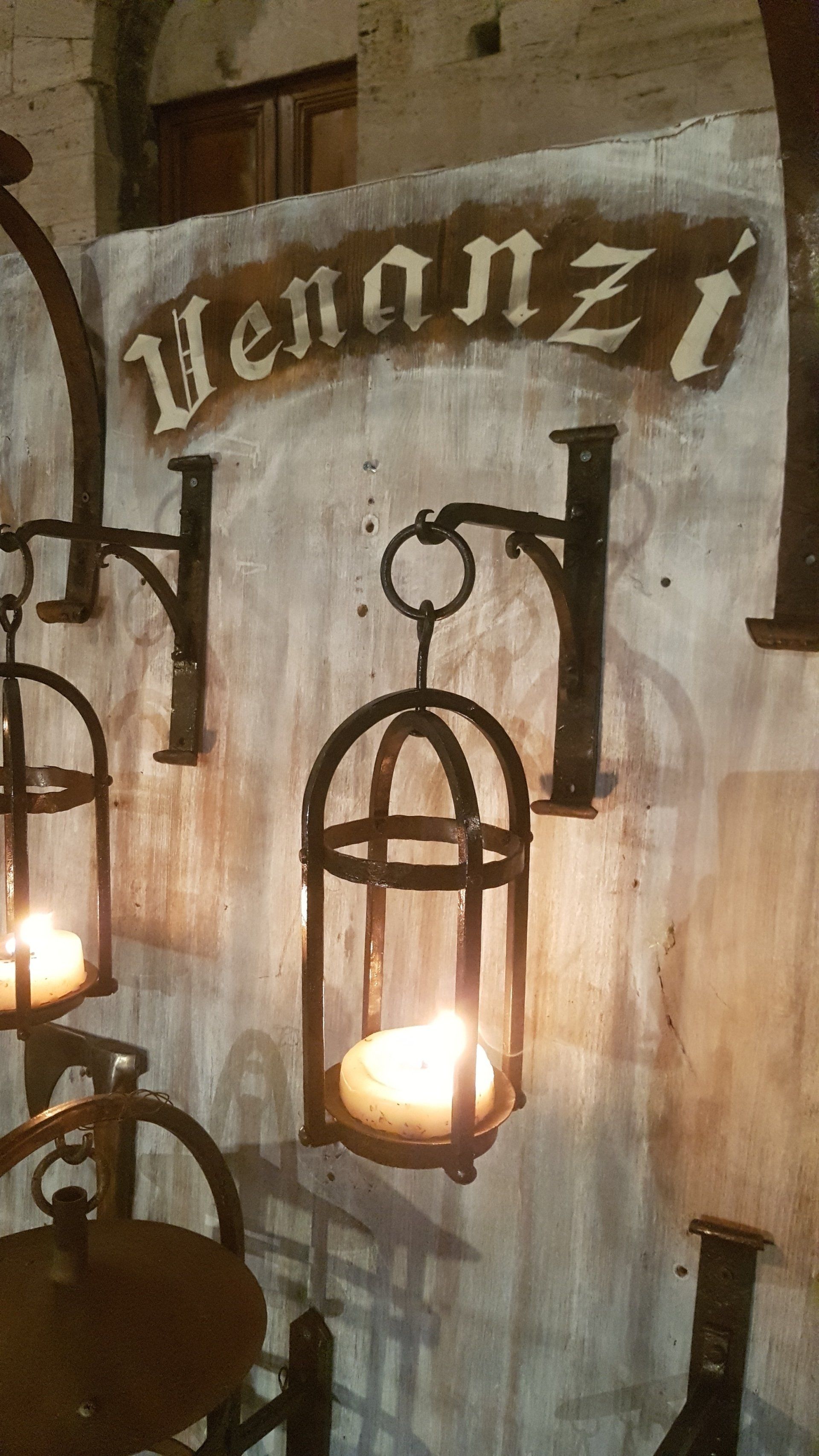Lanterna vintage illuminate contro un muro di pietra con un cartello di legno con la scritta
