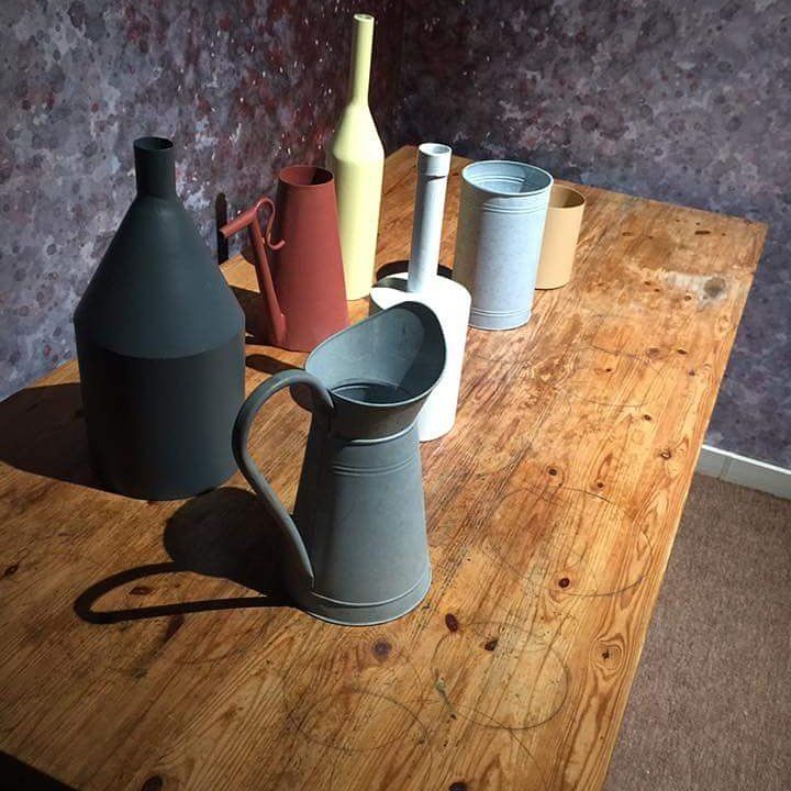 Brocche e vasi in ceramica assortiti nei colori nero, rosso, bianco e blu, su un tavolo di legno.